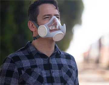 Man in blue shirt outdoors wearing OmniMask and looking into the distance.